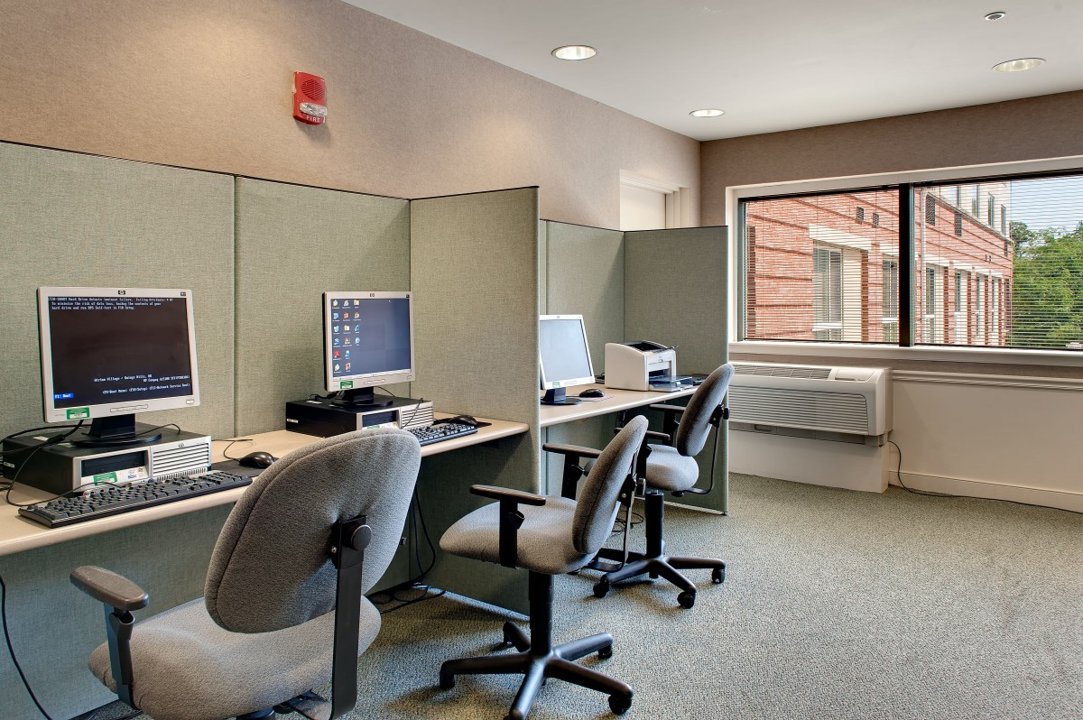 A small office with multiple computer workstations and chairs arranged in a row.