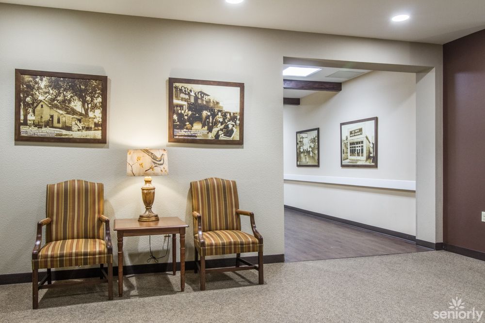 A lobby area with striped chairs, a lamp, and framed artwork leading to a hallway.