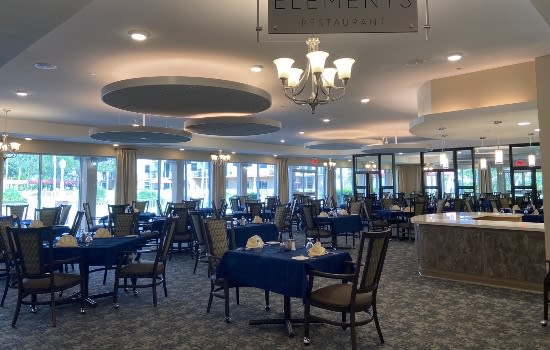 A spacious and elegantly decorated restaurant dining area with tables and chairs set for service.