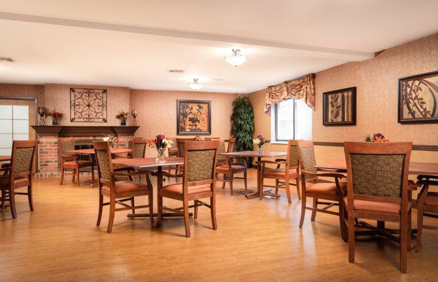 A cozy dining area with multiple tables and chairs, decorated with artwork and plants.