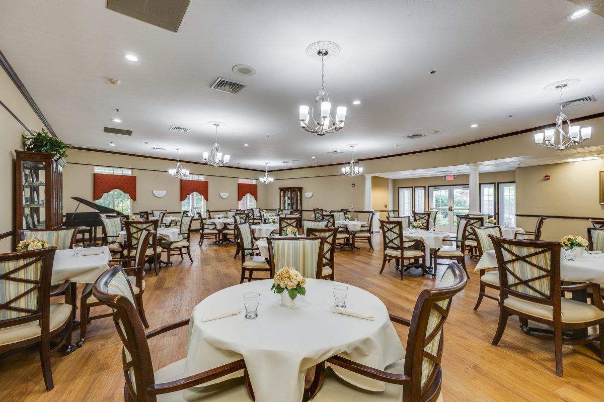 A spacious dining room with neatly arranged tables and chairs, featuring elegant chandeliers and decor.
