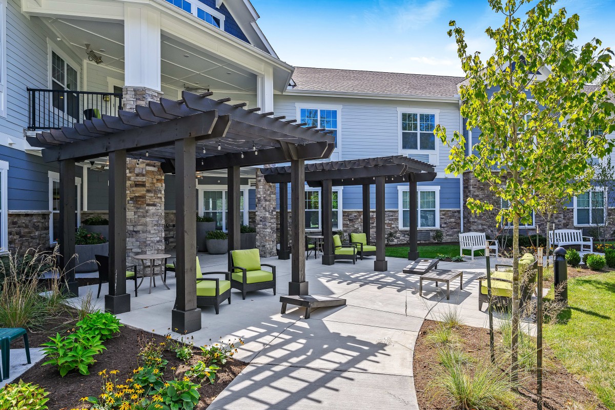 A modern apartment building featuring an outdoor patio with pergolas and comfortable seating areas.
