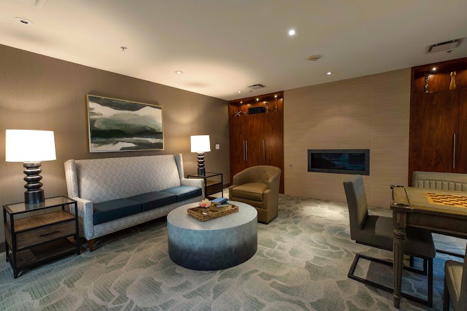 A modern living room with stylish furniture, including a sofa, armchair, and coffee table, complemented by a lamp and artwork on the wall.