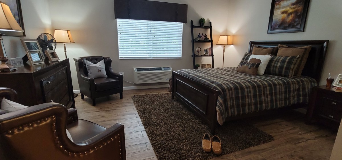 Cozy bedroom with a bed, armchair, and ambient lighting.
