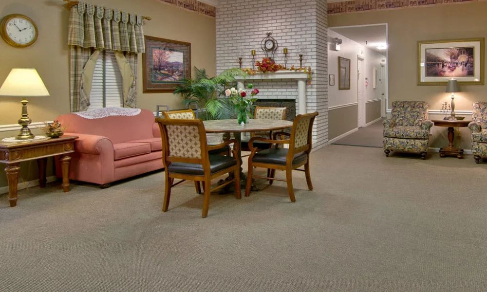 A cozy living room with a table and chairs, a sofa, and a fireplace.
