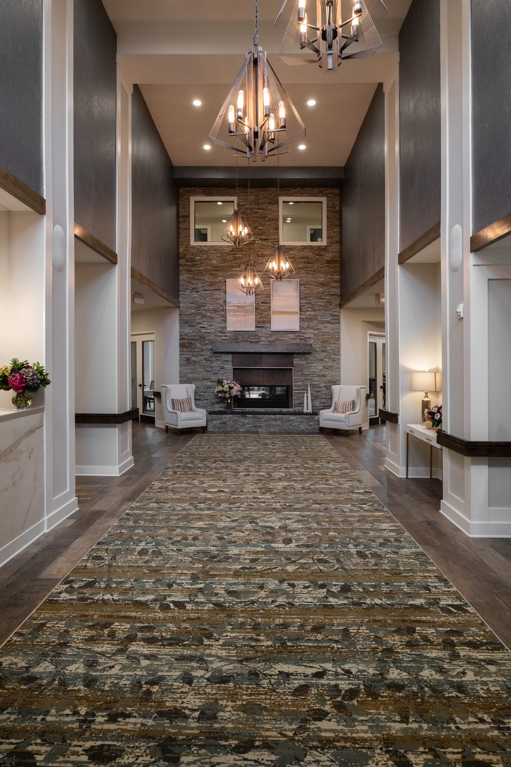 A luxurious living room with a tall stone fireplace and elegant chandeliers.