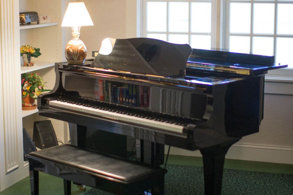 A grand piano with a lamp placed on top in a well-lit room.