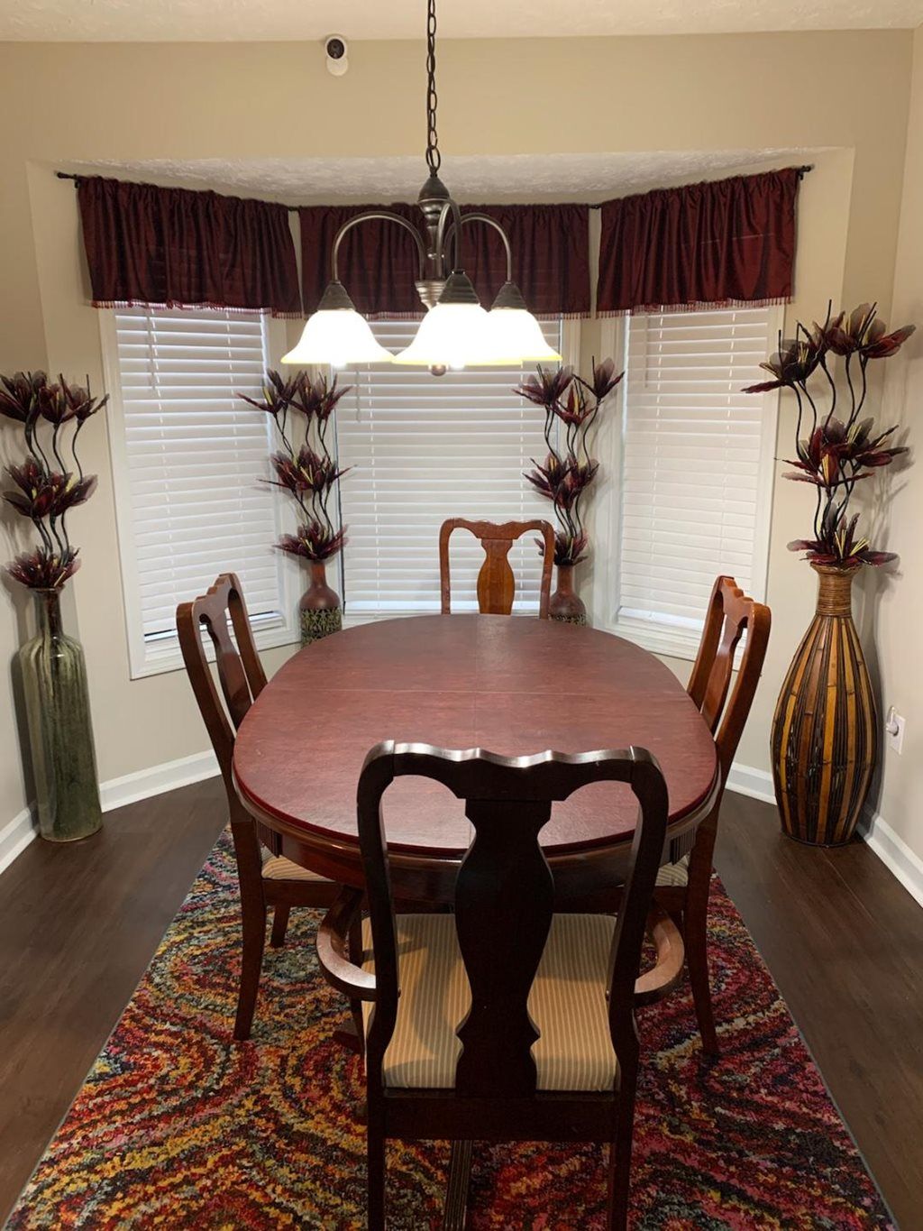 A classic dining room with a wooden table and chairs, accentuated by tall decorative vases and elegant lighting.