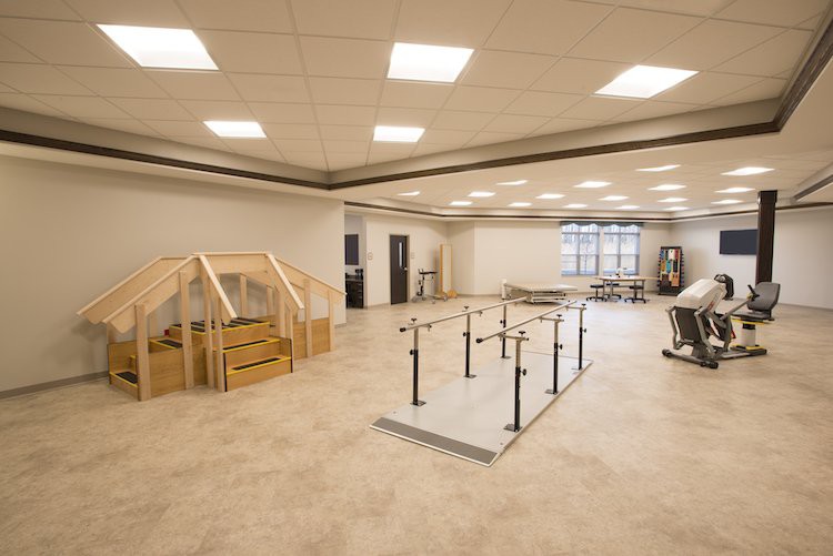 A spacious rehabilitation center with exercise equipment and handrails for physical therapy.