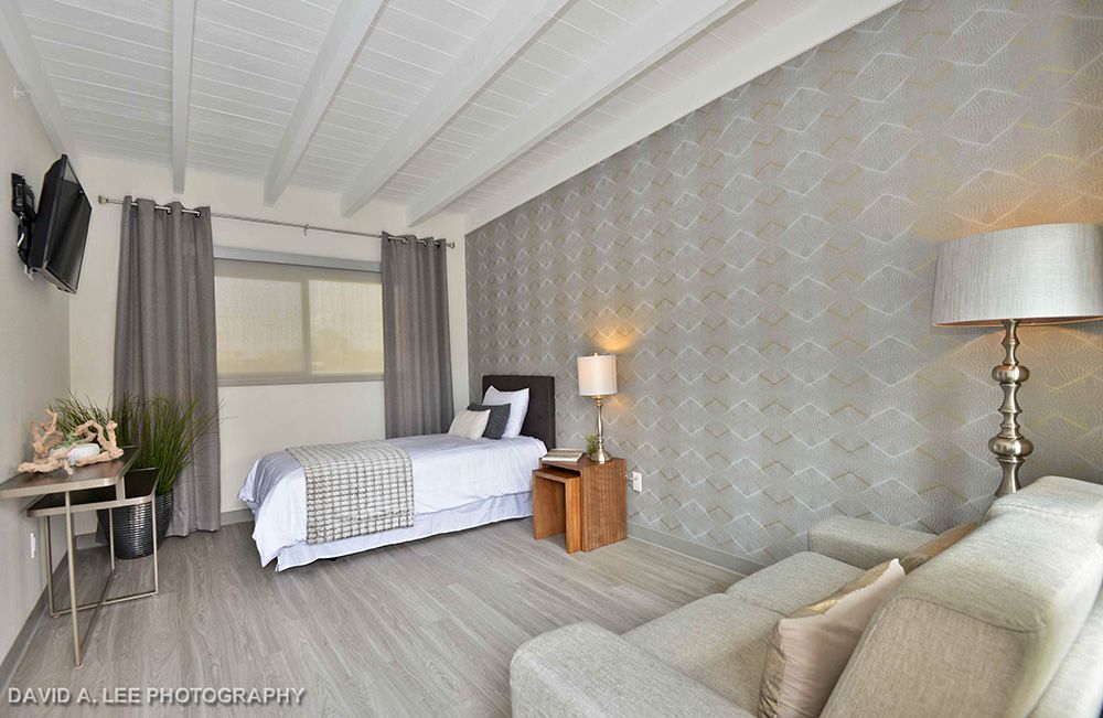 A modern bedroom with stylish decor, featuring a bed, bedside lamp, and sofa.