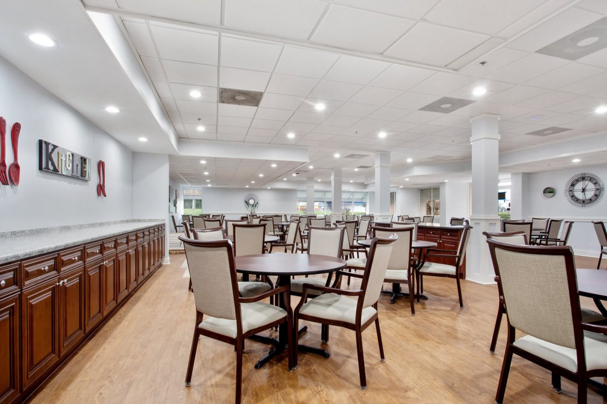A spacious dining area with neatly arranged tables and chairs under bright lighting.