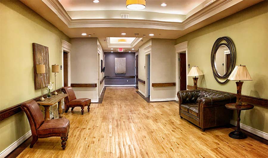 A well-lit hallway with wooden flooring and comfortable seating arrangements.