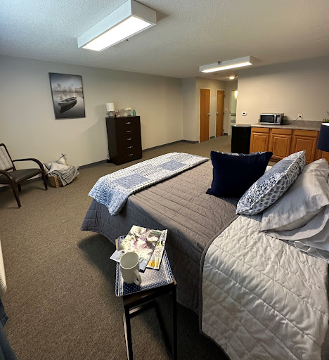 A spacious and inviting bedroom with a neatly made bed, comfortable seating, and warm decor.