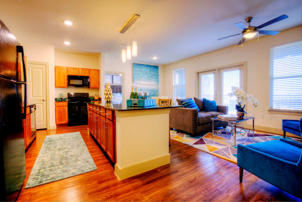 A modern open-layout living room and kitchen with hardwood floors and colorful decor.