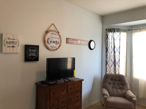 A cozy living room setup featuring a television, decorative wall art, and a comfortable chair by the window.