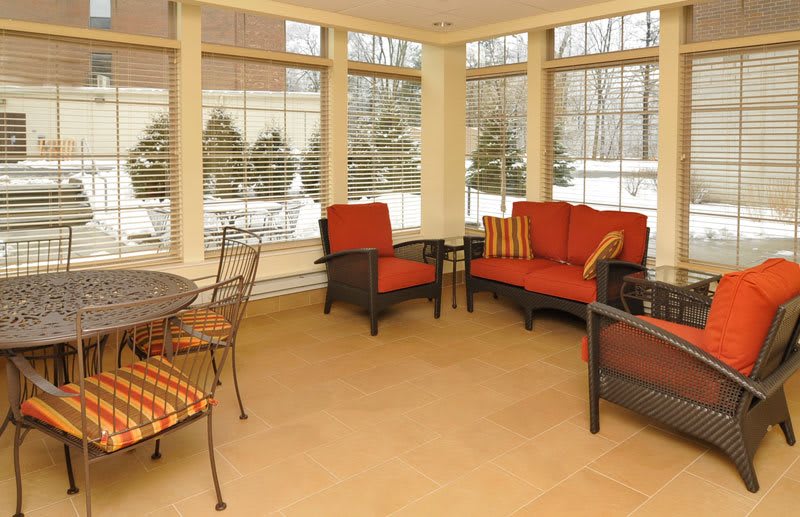A cozy sunroom featuring comfortable seating and large windows with outdoor views.