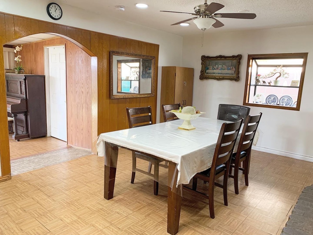 A cozy dining room with a wooden table and chairs, adorned with a ceiling fan and surrounded by windows.
