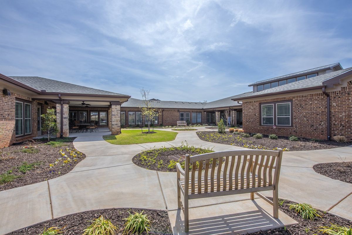 A peaceful courtyard with a bench surrounded by brick buildings under a clear sky.