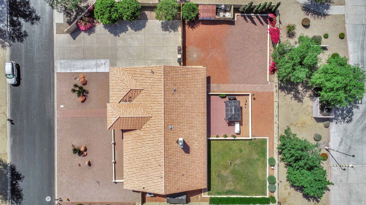 An aerial view of a residential property with a tiled roof, backyard, and driveway.