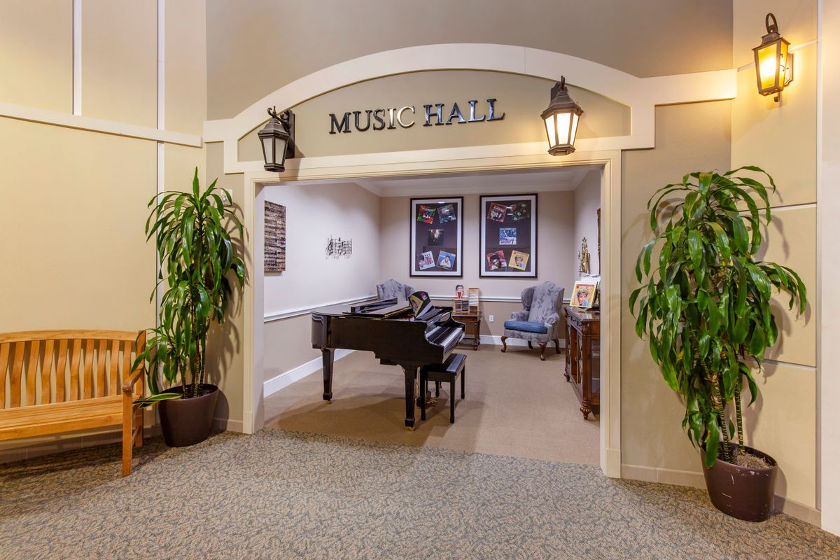 A cozy music hall with a grand piano, comfortable seating, and decorative plants.