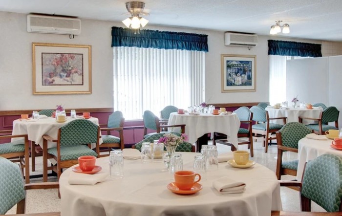 A well-set dining area featuring round tables with colorful cups and neatly arranged chairs.
