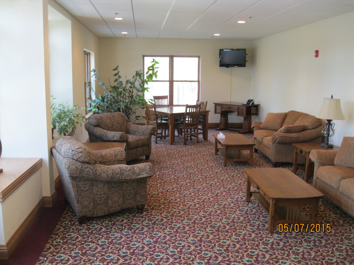 A cozy living room with comfortable seating, a patterned carpet, and a wall-mounted television.