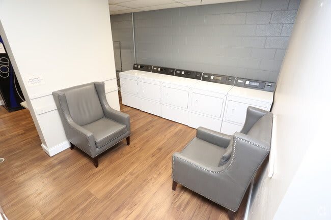 A clean laundry room with seating and washing machines.