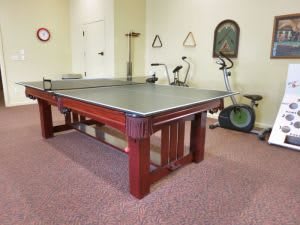 A recreation room featuring a ping pong table and an exercise bike.