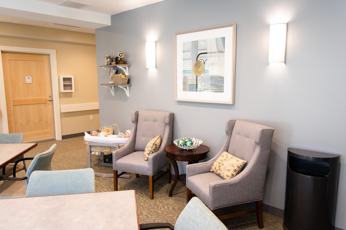 A cozy waiting room with modern decor, featuring plush chairs and a stylish painting on the wall.