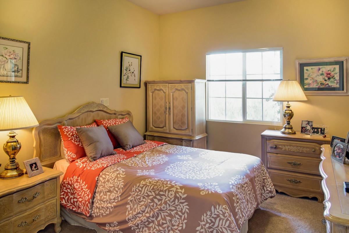 A cozy bedroom with a bed adorned with patterned bedding, a bedside lamp, and wooden furniture.