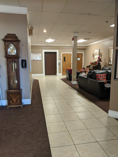 A spacious and welcoming lobby featuring a classic clock, comfortable seating, and an elevator.