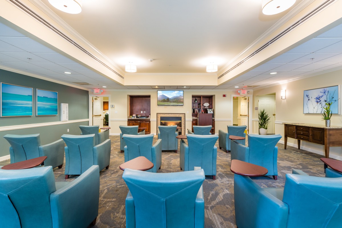 A well-lit waiting room with arranged seating and a central television.