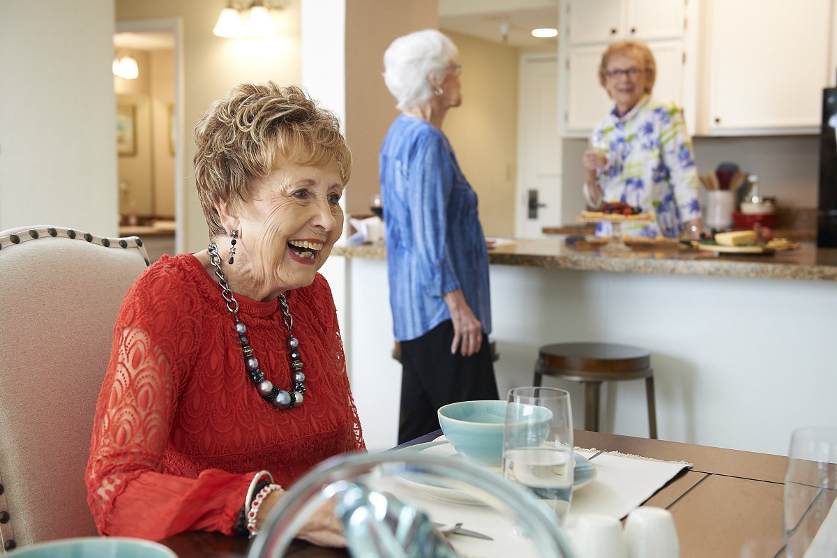 Elderly women enjoying a joyful conversation around a dining table.