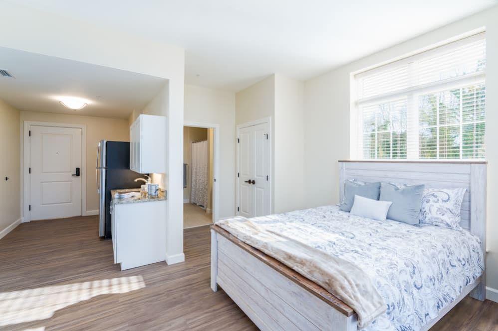 A bright and minimalist bedroom with wood flooring and natural light.