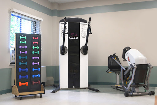 A well-equipped gym area featuring a cable machine and various weights.