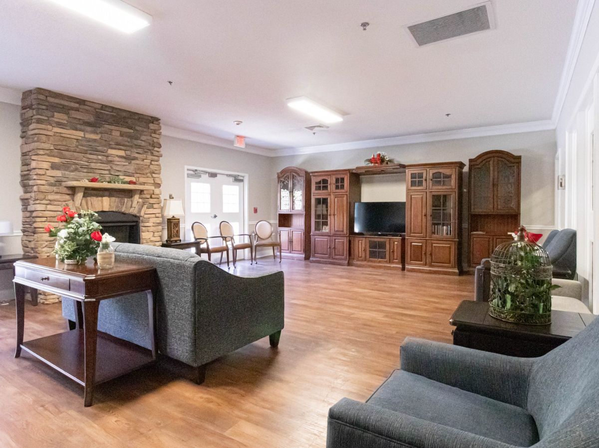 A spacious living room with wooden flooring, featuring a comfortable seating area, a television, and a fireplace.