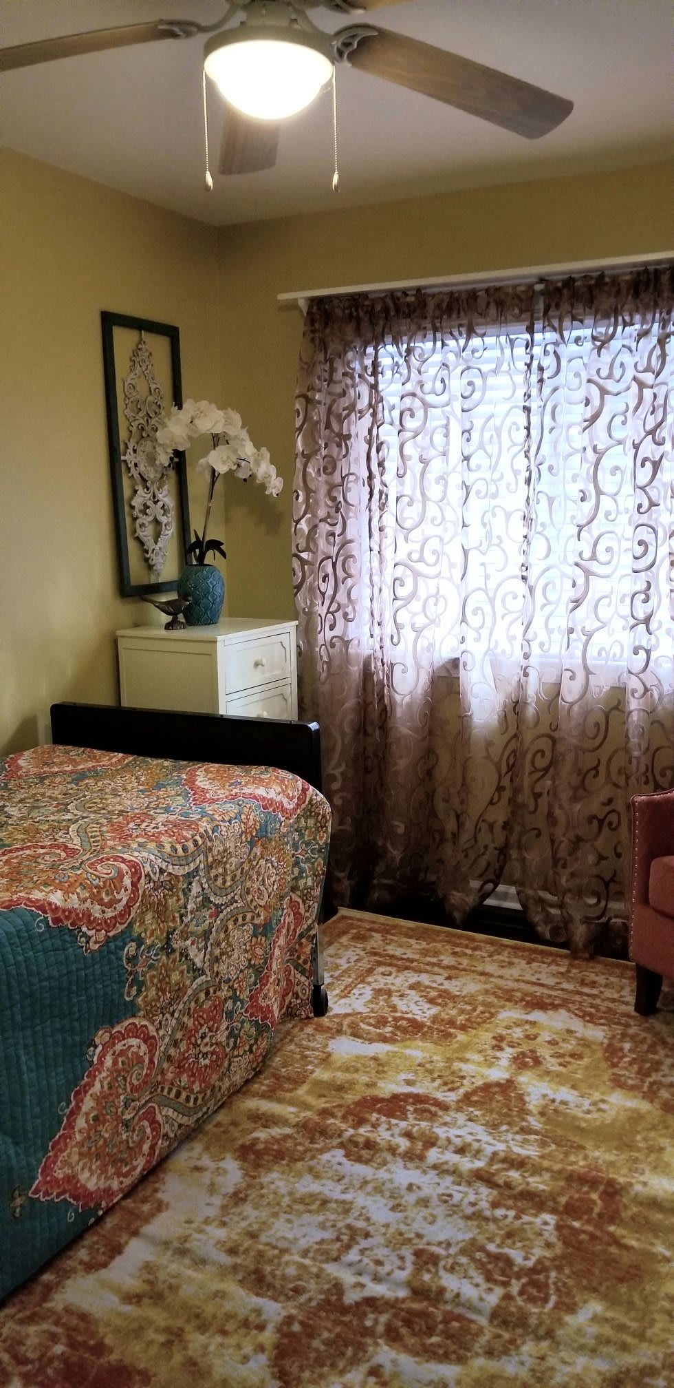 A cozy bedroom with patterned bedding and decorative curtains.