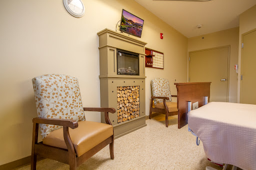 A cozy waiting area featuring comfortable chairs, a decorative fireplace, and a television.