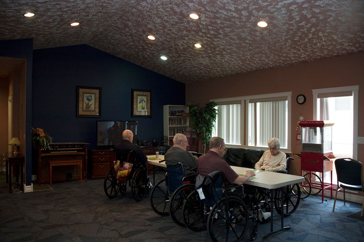 A group of seniors in wheelchairs gathered in a community room at a nursing home.