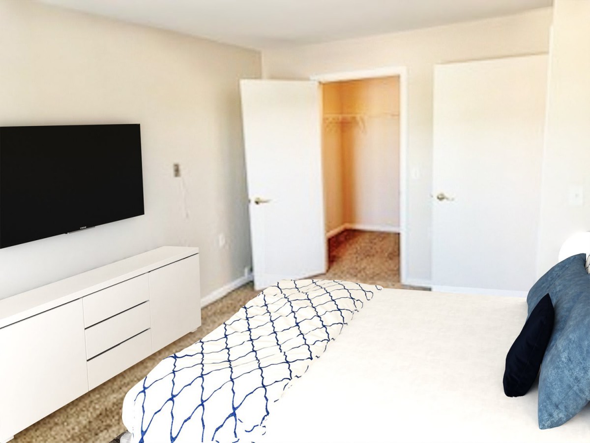 A minimalist bedroom with a TV and open closet.