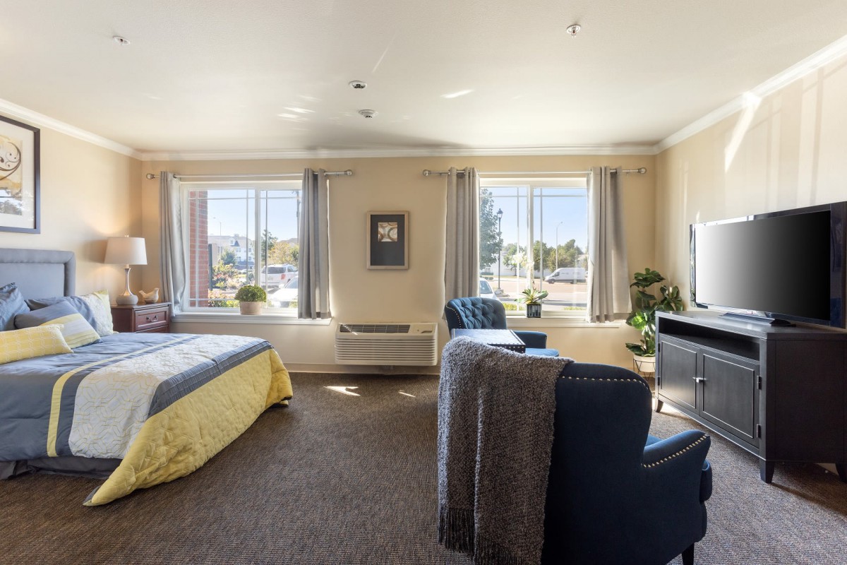 A spacious and well-lit bedroom with comfortable seating and elegant decor.