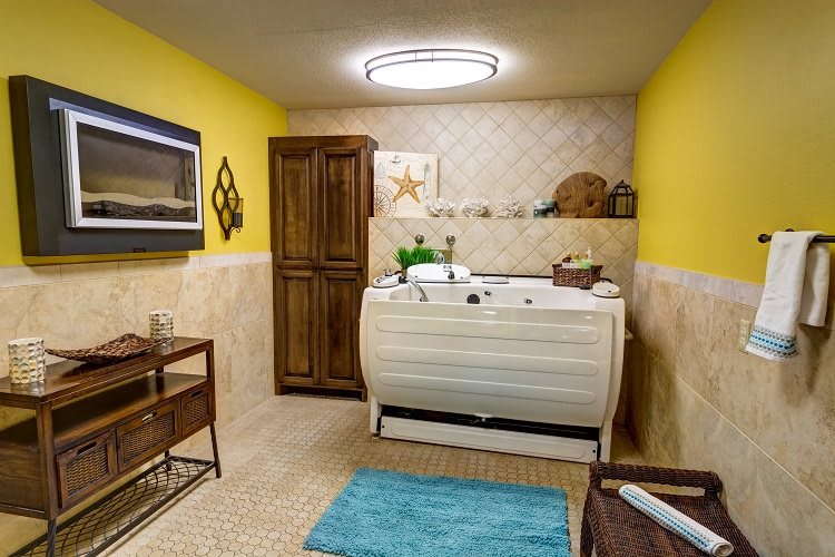 A cozy bathroom featuring a jacuzzi, vibrant yellow walls, and wooden cabinets.
