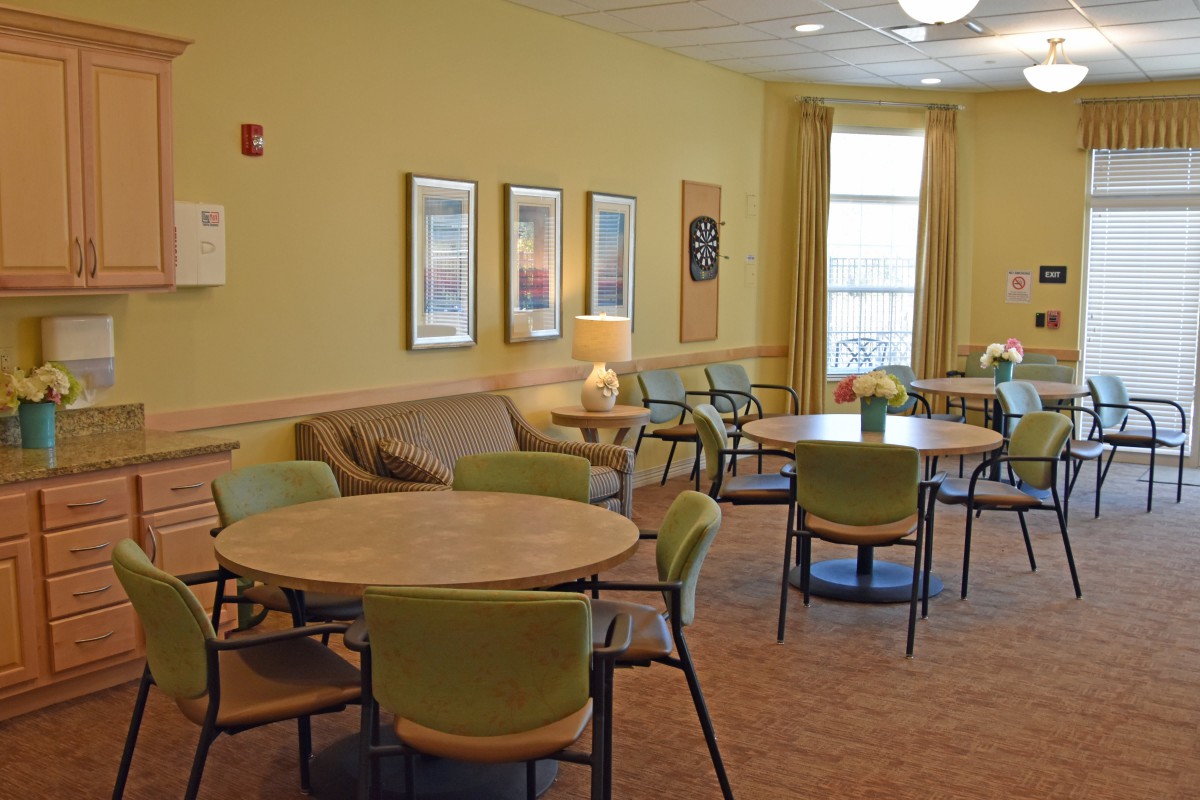 A cozy lounge area with tables and chairs arranged for seating, featuring warm lighting and wall decorations.