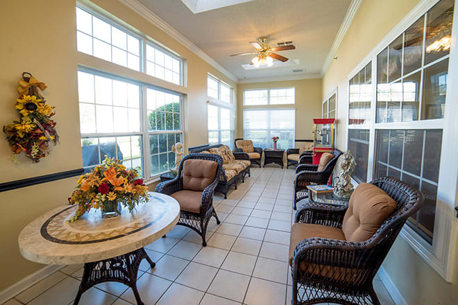 A bright sunroom with comfortable wicker furniture and large windows allowing ample natural light.
