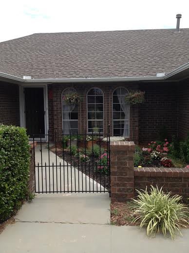 A cozy brick house with a small garden and a gated front yard.