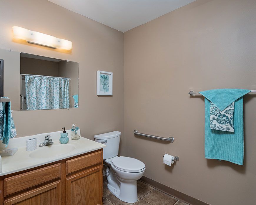 A neatly organized bathroom with a toilet, sink, and mirror.