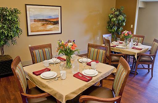 A beautifully arranged dining room with a table set for a meal, featuring flowers and comfortable chairs.