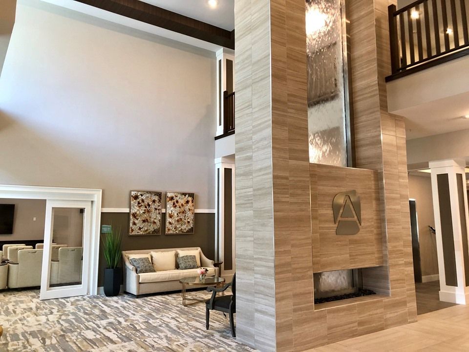 A modern living room with a high ceiling, featuring a sofa and decorative wall art.