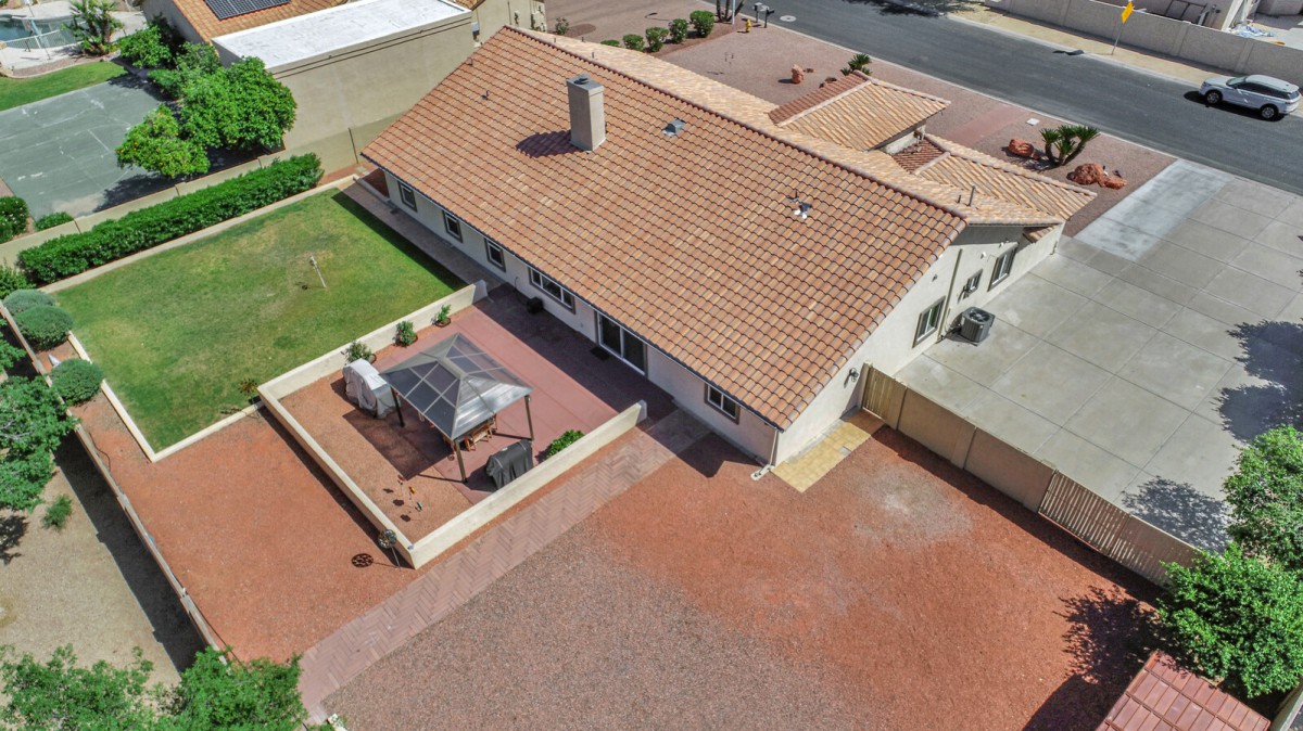 Aerial view of a house with a large roof, backyard, and patio area.