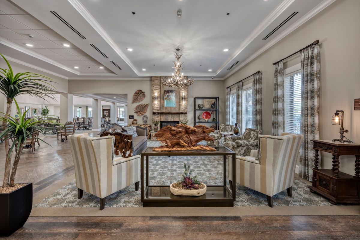 A luxurious living room featuring elegant furniture, a central chandelier, and large windows.